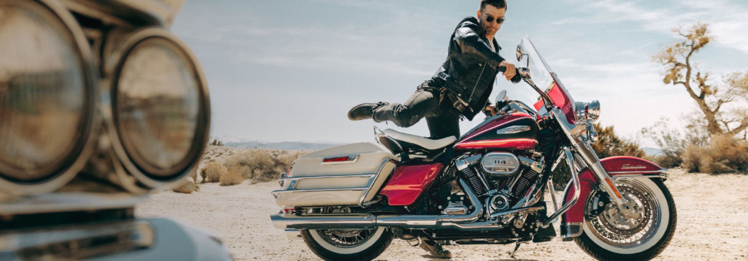 Rider mounting a Harley-Davidson Electra Glide Highway King in a desert landscape.